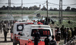 Palestinian demonstrators throw stones at an Israeli bunker as another waves a national fl...