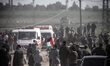 Palestinian demonstrators throw stones at an Israeli bunker as another waves a national fl...