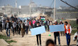 A Palestinian demonstrator throws back a tear gas canister as others run from gas fired by...