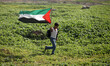 A Palestinian demonstrator throws back a tear gas canister as others run from gas fired by...