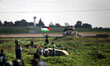 A Palestinian demonstrator throws back a tear gas canister as others run from gas fired by...