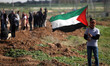 A Palestinian demonstrator throws back a tear gas canister as others run from gas fired by...