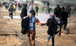 A Palestinian demonstrator throws back a tear gas canister as others run from gas fired by...