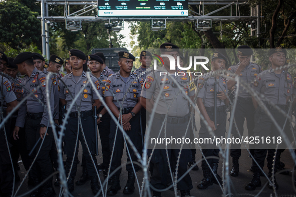Police guard behind a barbed wire in a May Day rally in Jakarta on May 1, 2019.  Thousands of Indonesian workers are urging the government t...