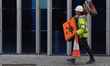 A construction worker carries a safety equipment, signs and cones, to secure the safe traf...