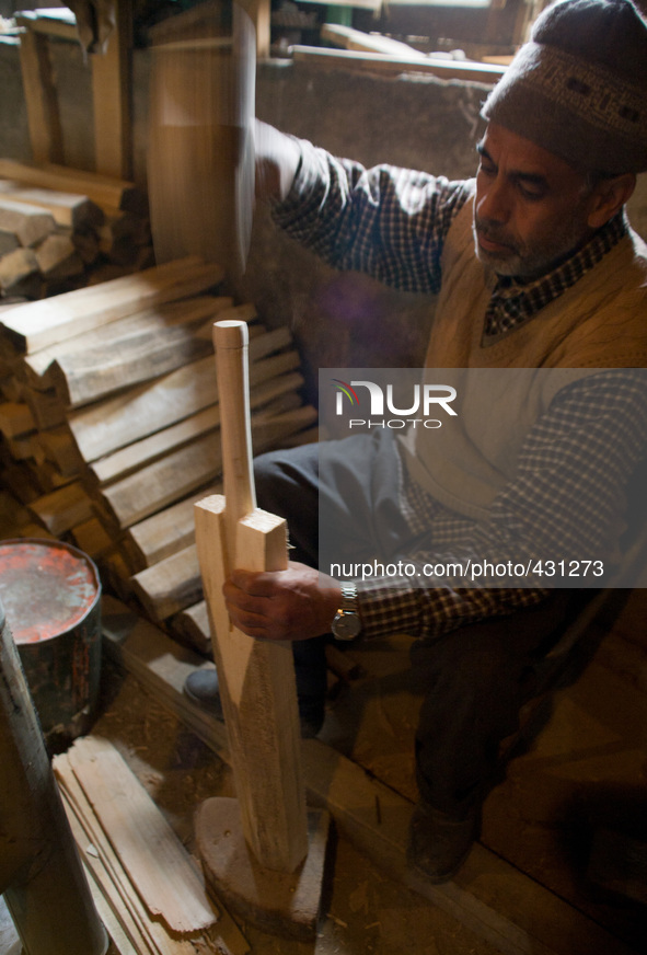 HALMULLAH, INDIAN ADMINISTERED KASHMIR, INDIA - FEBRUARY 11: A workers fixes handle to an unfinished cricket bat in a bat factory on Februar...