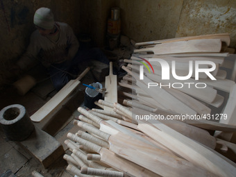 HALMULLAH, INDIAN ADMINISTERED KASHMIR, INDIA - FEBRUARY 11: A workers loops handles of cricket bat  with thread in a bat factory on Februar...