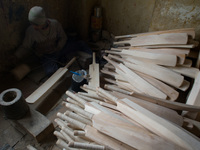 HALMULLAH, INDIAN ADMINISTERED KASHMIR, INDIA - FEBRUARY 11: A workers loops handles of cricket bat  with thread in a bat factory on Februar...