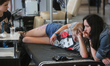 A girl comforts the girlfriend while the master tattoos her during the tattoo festival in...