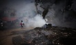 Bangladeshi people seen walking as toxic garbage are burning besides a road near Buriganga...