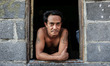 Thai guy watching through the window of his house which is located front of the railway, o...
