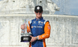 Scott Dixon (9) of New Zealand and Chip Ganassi Racing holds the winner’s trophy after tak...