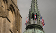 French, British and U.S. flags attached to the tower of the Cathedral of Our Lady of Bayeu...