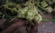 A seller offers a woven diamond shaped palm leaf pouch “ketupat” to be cooked as rice pouc...