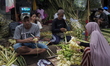 Sellers offer a woven diamond shaped palm leaf pouch “ketupat” to be cooked as rice pouch...