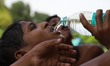 A boy drinks water from a bottle on a hot summer day in New Delhi on 15, June 2019 