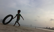A boy plays with a rubber tyre along the Arabian Sea in Mumbai, India on 23 June 2019. 