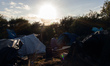 A man prays in a base camp in an area known as "the jungle" which is closer to the port th...
