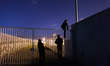 Three migrants start jumping the fences to access the port's truck parking lot. Calais, Fr...
