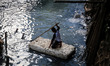 A boy sitting on a makeshift raft play in a river during a month-long break from school in...