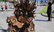 A street entertainer dressed in the Pumbaa costume looks at the iron Throne installed at I...