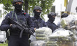 Ukrainian police officers stand guard in front of bags of cocaine seized during a special...