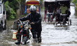 Commuters wade through waterlogged street during a heavy rainfall in Guwahati, Assam, Indi...