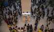 People are seen surrounding a pillar where protesters have place notes on it in a shopping...