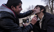 An Afghan man has his beard shaved off before attempting to cross into Hungary from Serbia...