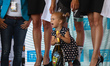 Maja, the daughter of Rafal Majka of Poland and team Bora-Hansgrohe, helps to open the bot...