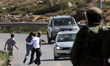 A member of the Israeli security forces looks on as Israeli settlers throw stones at the c...