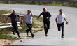 Armed Israeli settlers run on the road leading to the al-Jalazun Palestinian refugee camp,...