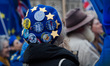 A pro-EU demonstrator wears a hat adorned with anti-Brexit badges during a protest outside...