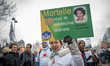 A health insurance card holding as a sign by a protestor with a close up of marisol tourai...