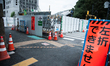 People are seen walking past the building of the Olympic Stadium of Tokyo, who will host t...