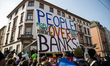 A protester holds a banner "People over banks" on the opening day of the European Central...