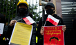 Demonstrators are seen holding signs and Polish flags during a rally against Chinese gover...