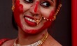 An Indian Hindu devotee smiles as she is smeared with vermillion powder as part of a ritua...