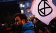 A member of climate change activist group Extinction Rebellion (XR) carries an XR flag on...