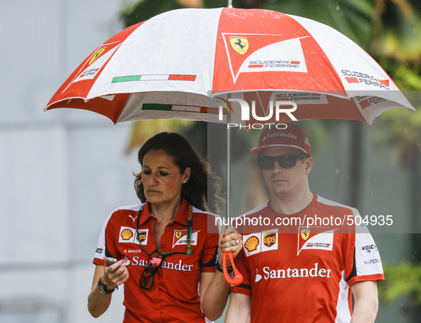 Finnish Kimi Raikkonen (R) of Scuderia Ferrari walks with his team member during the Malaysian Formula One Grand Prix at Sepang Internationa...