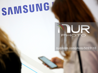 The Samsung logo is pictured as a woman checks the phone during the annual Web Summit technology conference in Lisbon, Portugal on November...