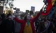  A man dressed as the Joker and holding a Mapuche flag cheers with others dressed in costu...