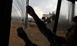 A Palestinian boy pulls glass shards from a broken window at his home near the site of Isr...