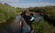 A woman with her child crosses the Rio Bravo, Mexico, to reach the United States surrender...