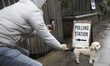 A man takes a picture of his dog next to a polling station sign on the day of General Elec...