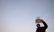 An Iranian man holds-up a portrait of Qasem Soleimani during a mass funeral for the comman...