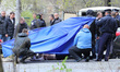 Police experts examine the body of prominent pro-Russian journalist Oles Buzyna, 45, after...