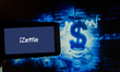The logo of iZettle is seen on a screen of a smartphone next to an illustration of money a...