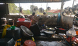 An elderly lady cleans dishes in the kitchen of a small restaurant near Phouthorng roundbo...