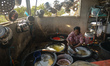 A portrait of an elderly lady cleaning dishes in the kitchen of a small restaurant near Ph...